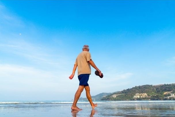 Imagen de una persona mayor caminando por la playa